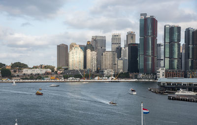 Boats in sea against modern buildings in city