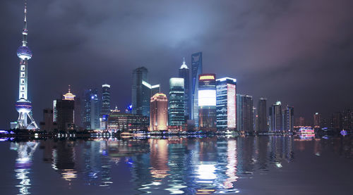 Illuminated buildings in city against sky at night