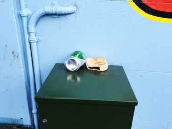 Abandoned drink can by bread on table against wall