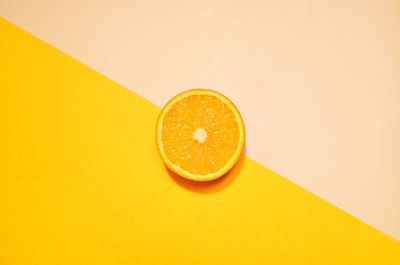 High angle view of lemon and orange on yellow background