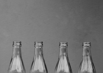 Close-up of empty glass bottles against concrete wall