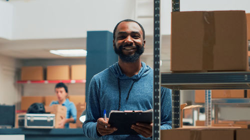 Portrait of young man using mobile phone while sitting in office