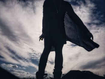 Low section of silhouette man walking against sky