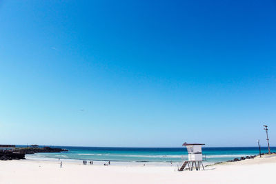 Scenic view of beach against clear blue sky