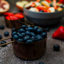 Close-up of blueberries in measuring cup on table with assortment of fruit