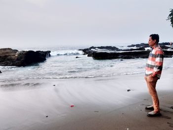 Full length of woman standing on beach against sky