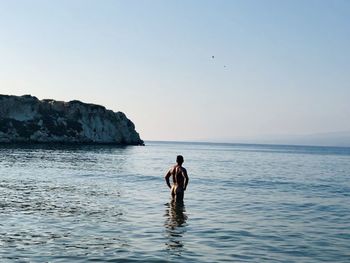 Rear view of naked man standing in sea