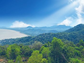 Scenic view of mountains against the beach and blue sky