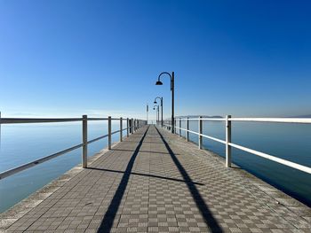 Pier over sea against clear blue sky