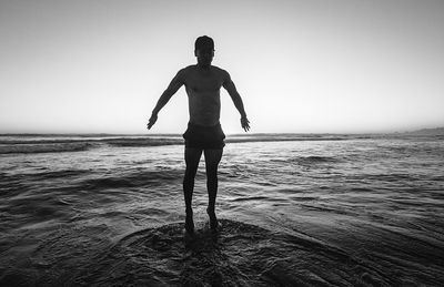 Rear view of silhouette man standing at beach