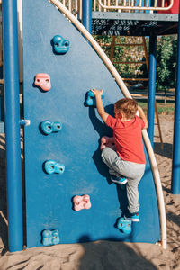 Rear view of boy on slide at playground