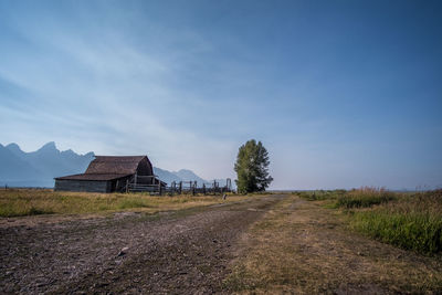 Built structure on field by road against sky