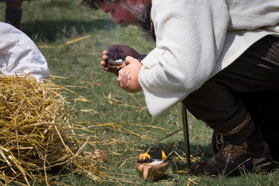 Midsection of man holding leaf on field