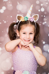 Portrait of cute girl smiling against wall