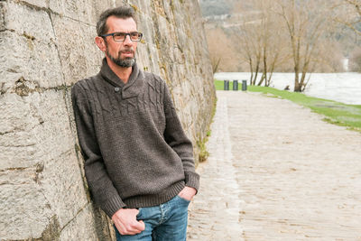 Portrait of smiling man standing by brick wall