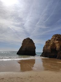 Rock formation on beach against sky