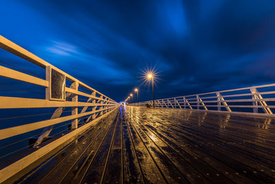 Light trails on bridge against sky at night