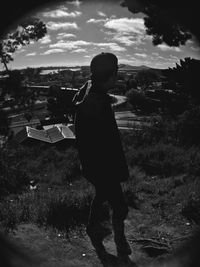 Rear view of boy standing on land against sky