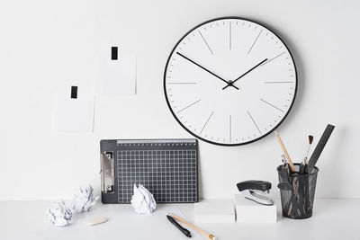 Low angle view of clock on table against white wall