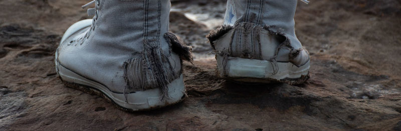 Low section of person wearing torn shoes