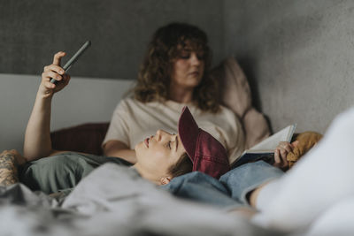 Lesbian woman using smart phone while lying down on girlfriend's lap at home