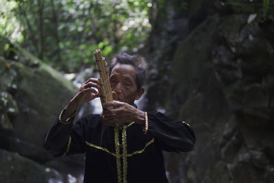  dusun ethnic grandpa , sabah, plays traditional bamboo musical instruments 