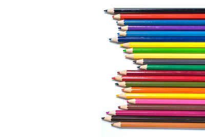 Stack of multi colored pencils on table against white background