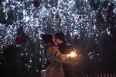 Rear view of friends standing against illuminated lights