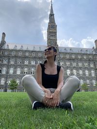 Woman sitting on lawn against building