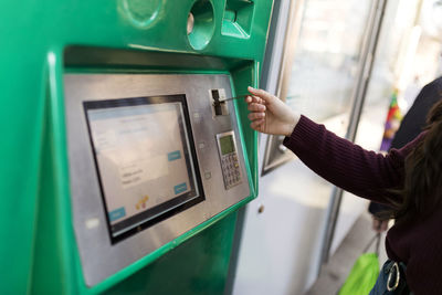 Woman buying ticket from vending machine at tram station