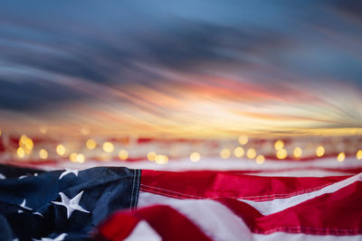 Close-up of illuminated flags against sky during sunset