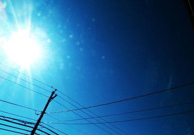 Low angle view of power lines against blue sky