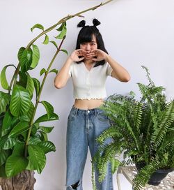 Young woman standing against plants