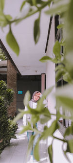 Woman standing by tree outside house