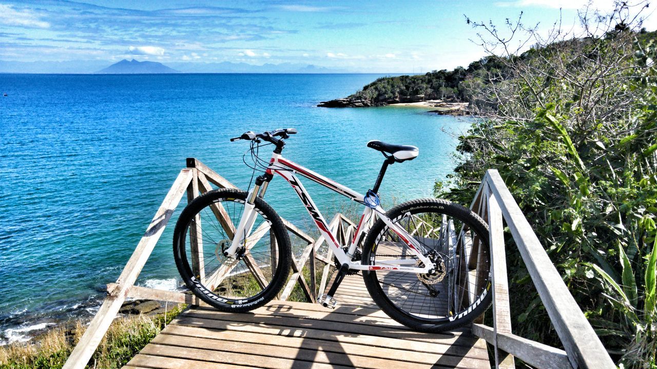 bicycle, water, sea, transportation, mode of transport, land vehicle, parked, parking, tranquil scene, stationary, scenics, sky, nature, blue, tranquility, beauty in nature, calm, outdoors, day, remote, cliff, summer, shore, no people, seashore, solitude
