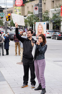 Full length of friends standing on road in city