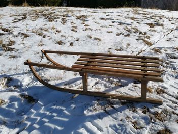 Empty bench on snow covered field