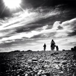 People standing on landscape against cloudy sky