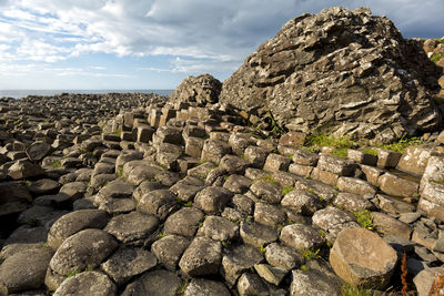 Stone wall by rocks against sky