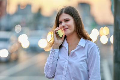 Portrait of smiling woman standing against city in background