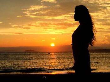 Silhouette woman standing on beach during sunset
