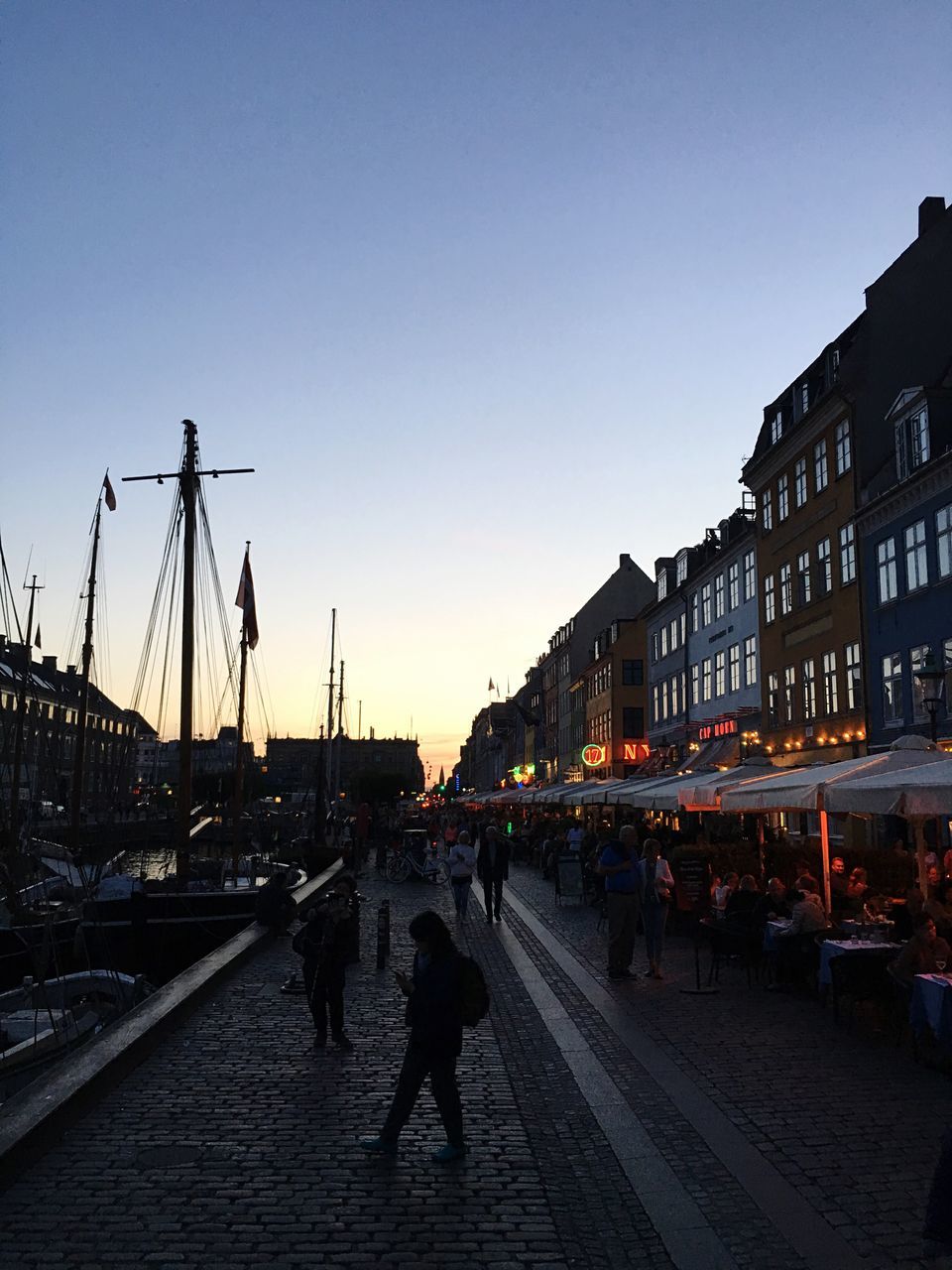 architecture, building exterior, built structure, clear sky, city, dusk, illuminated, footpath, the way forward, city life, town square, walkway, outdoors, person, old town, pedestrian walkway, diminishing perspective