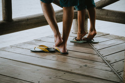 Low section of people wearing flip-flops on wooden floor