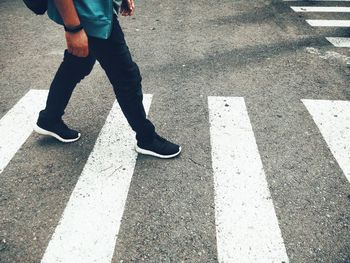 Low section of man walking on crosswalk