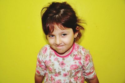 Portrait of smiling girl against yellow wall