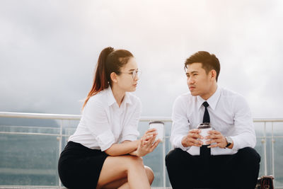 Business colleagues talking during coffee break against sky