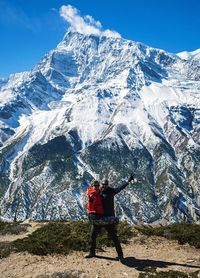 Man standing on snowcapped mountain against sky