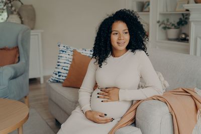 Portrait of smiling woman sitting on sofa at home