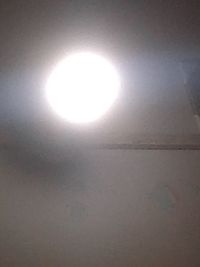 Low angle view of illuminated lamp against wall at night