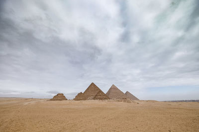 Egyptian pyramids against cloudy sky